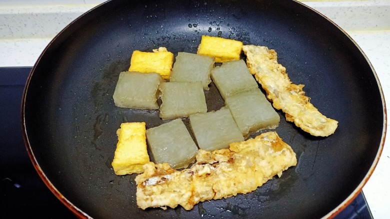 皮渣炒豆腐、带鱼、蒜苔、胡萝卜,煎至两面金黄,放入豆腐、带鱼