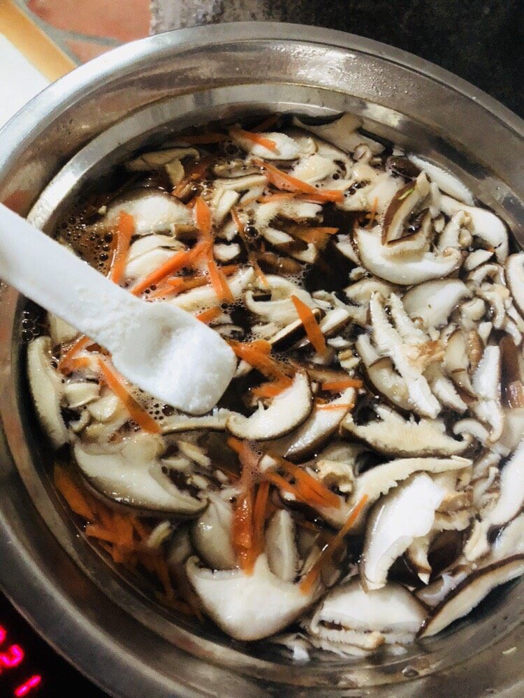 香菇豆腐汤,放入胡萝卜丝和香菇片,再放入适量盐,煮开。