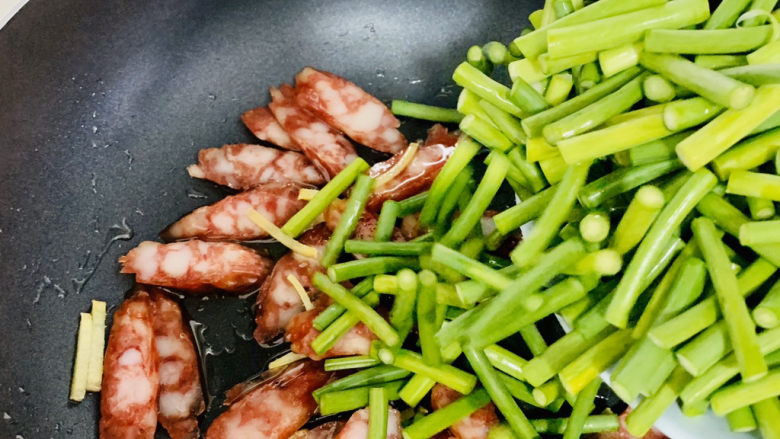 蒜苔炒腊肠,下入蒜苔,继续中火翻炒。