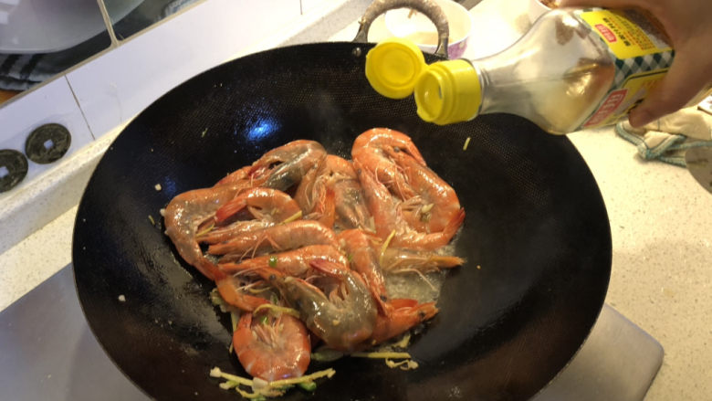 油焖大虾,倒入料酒翻炒均匀,再倒入适量清水。