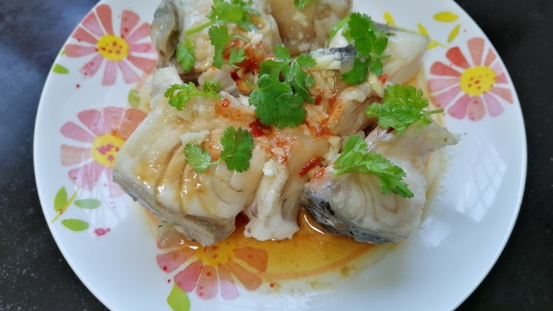 清蒸草鱼,将热油浇在鱼上,放上香菜点缀
