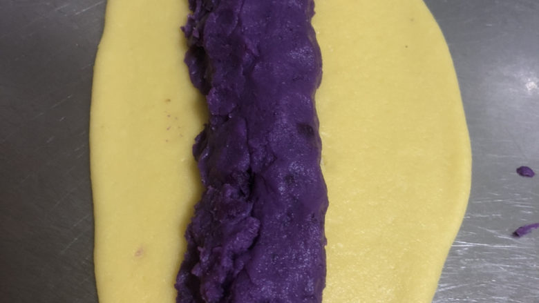 紫薯一口酥,拿出面团,均匀将面团分成两份,搓成长条,擀成椭圆形面片,长约22厘米左右,再将<a style='color:red;display:inline-block;' href='/shicai/ 6364'>紫薯馅</a>搓成长条卷入面片中,一定要包紧,将面片捏紧,搓成圆条,两边封口后切成2.5厘米的小剂子。