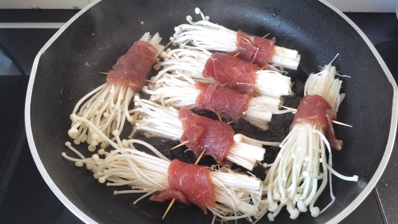 金针菇牛肉卷,锅里倒入少许油,油热放金针菇两面煎一下