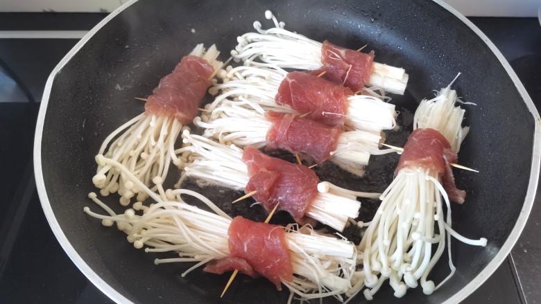 金针菇牛肉卷,锅里倒入少许油，油热放金针菇两面煎一下