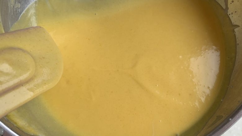 芒果慕斯蛋糕,将融化有吉利丁片的芒果泥分三次加入打发好的淡奶油中,不断搅拌,混合均匀。