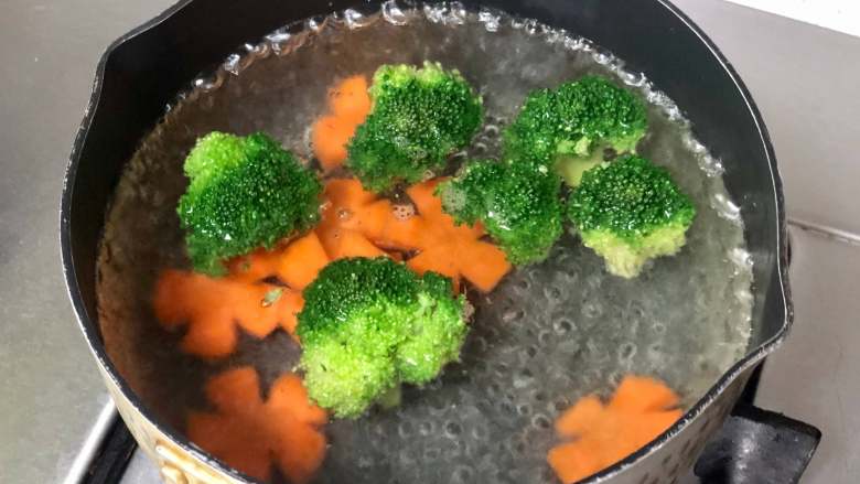 日式照烧鸡肉便当,荤素搭配营养低脂,好吃不胖!,锅里烧开水,下入西兰花和胡萝卜片焯熟,然后捞起过凉水,这样能让西兰花的颜色翠绿,口感也更爽脆。