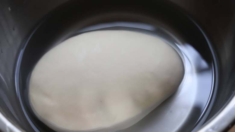 凉皮,把醒好的面团放入干净的大碗中,倒一些清水进来洗面,水量不需要很多,因为这个步骤我们要重复很多次,洗面的时候没有什么诀窍,来回折叠,抓捏就可以了。