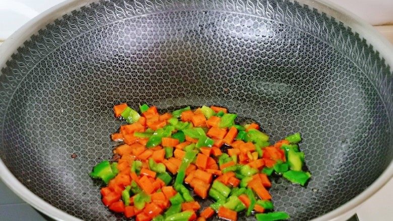 醋泡花生米,锅中留底油,加入胡萝卜丁青椒丁快速翻炒1分钟,盛出晾凉。
