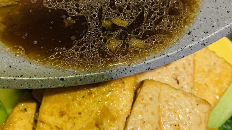 油菜豆腐,把煮好的豆腐夹起,放入装有油菜的盘子,并把锅里的料汁倒入;