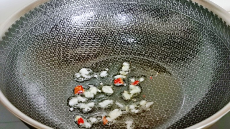 辣白菜炒土豆片,起油锅,加入蒜末炒香,辣椒炒香。