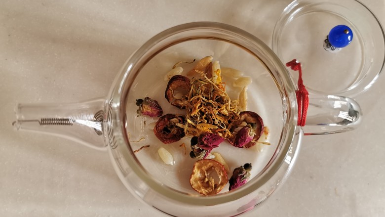玫瑰花茶,花草放进玻璃壶,用开水快速的洗两遍,去除细微的杂物污垢。