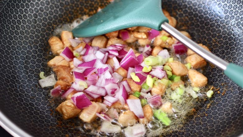 鸡丁核桃菠菜炒饭,大火快速翻炒至鸡肉丁断生变色,加入洋葱和小葱,继续翻炒均匀。