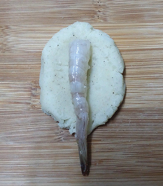 鲜虾饼,取适量土豆泥压扁,再把腌好的大虾放在上面包裹好,