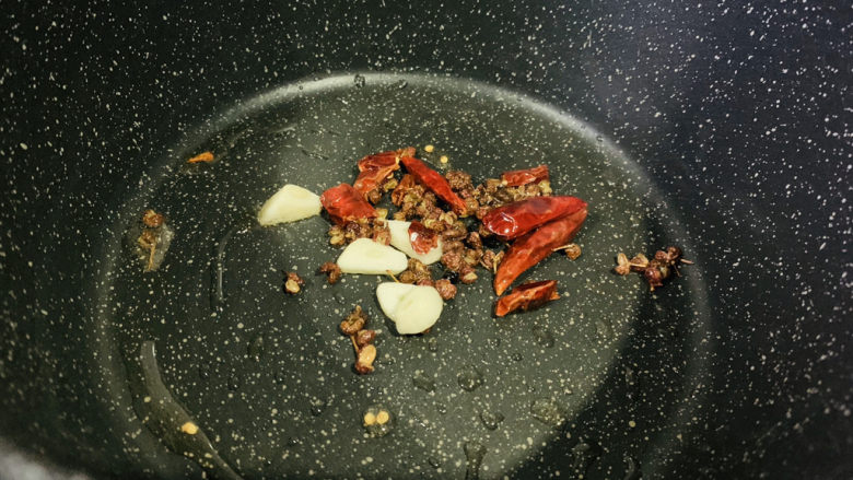 酸辣黄瓜条,锅里少许油,蒜瓣切片,和干辣椒花椒一起放入锅内,小火炒香;