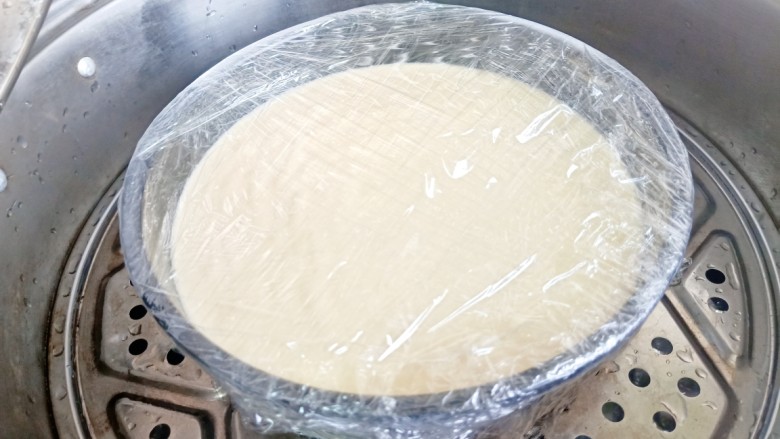 草莓酸奶蒸蛋糕,纸倒入模具中震荡几下把大气泡震出,盖上保鲜膜。