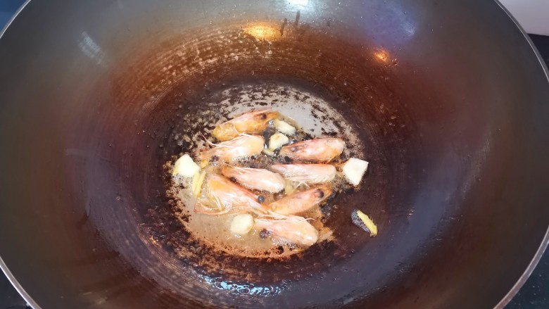 鲜虾砂锅粥,另起锅倒入油,放入姜丝蒜片爆香,倒入虾头炒出虾油