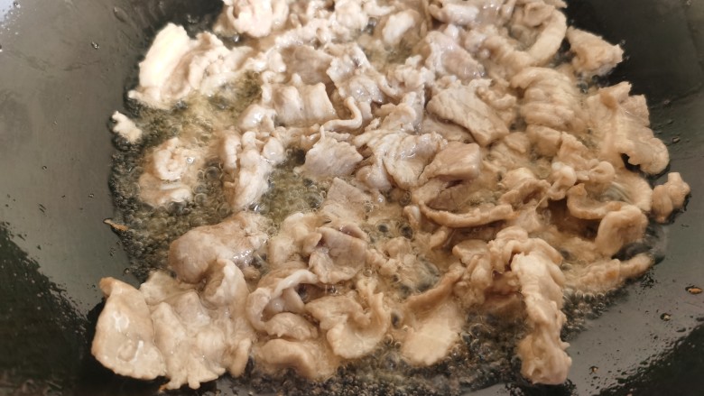 黄瓜木耳炒肉,炒锅放油,加入提前腌制的肉片炒至变色。