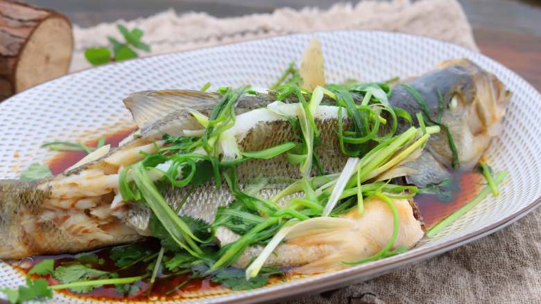 清香蒸鲈鱼,锅中倒入一勺油,油温烧至八成热,趁热浇在鱼身上即可上桌。
