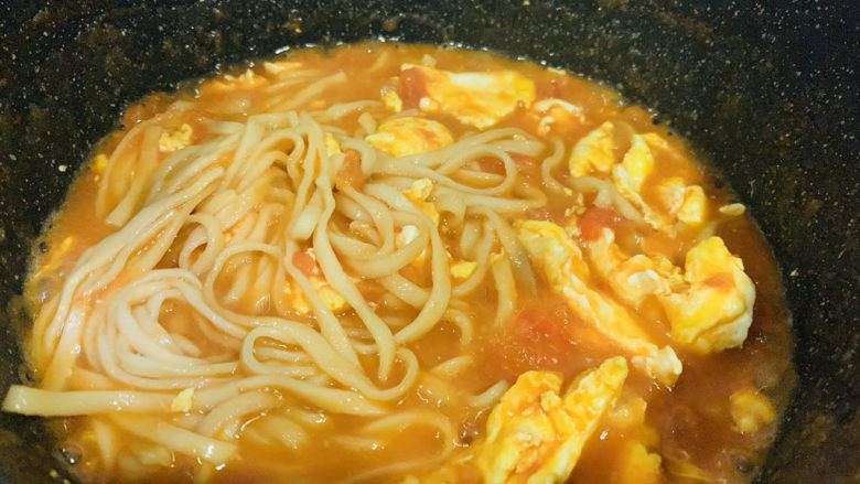 鸡蛋西红柿打卤面,用筷子翻拌面条,面条和汤料融合一起;