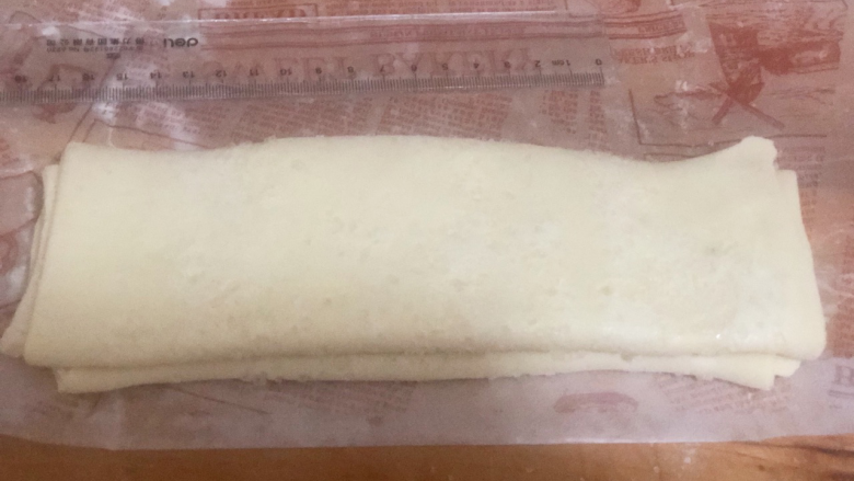 美味蝴蝶酥,将面皮翻面,以面皮中心线向外三等分,从三分之一处向内折叠,再折叠,最后对折 我折的有点丑然后放入冰箱冷冻20分钟。