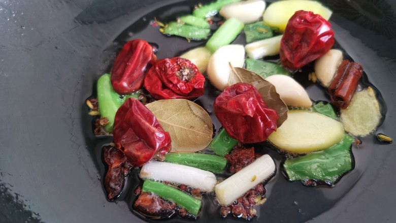 红焖牛肉,锅里放油,加入葱、姜、蒜、花椒、八角、辣椒炒香。