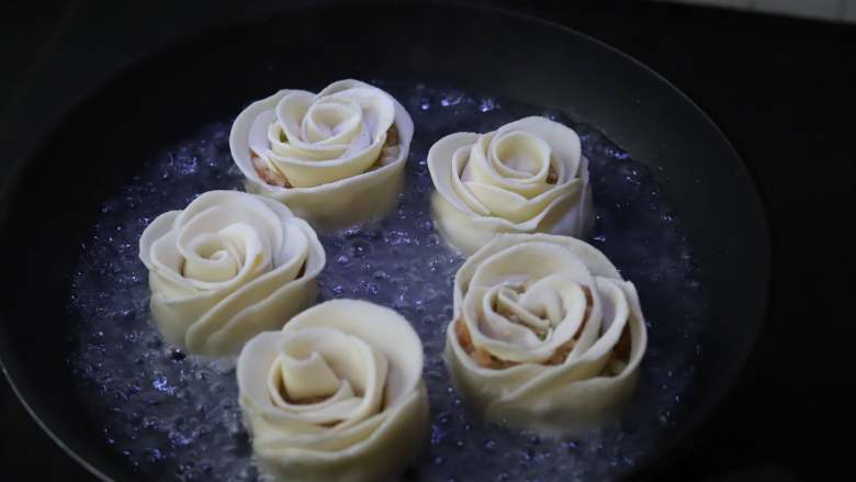 玫瑰花煎饺,平底锅中刷一层薄薄的油,摆入玫瑰花饺子,中小火煎至底部略带焦黄,然后加入一碗清水,水量能没住饺子大概三分之一的位置就差不多了,盖上锅盖,中火将水分烧干。