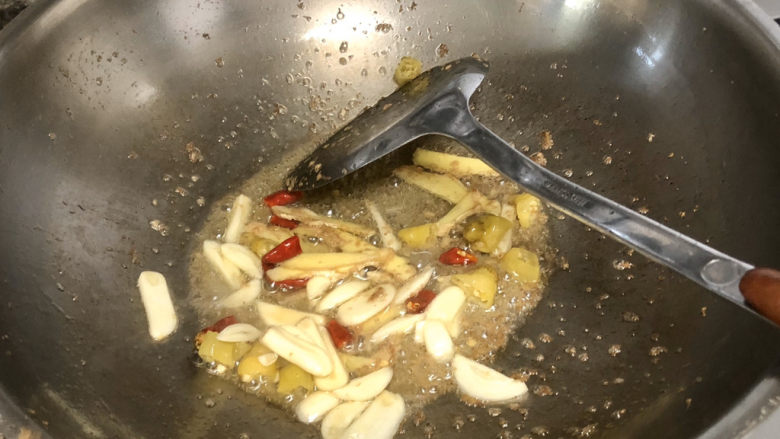 青椒炒猪肝,热锅冷油,加入蒜片姜片泡椒干辣椒小火煸炒一分钟