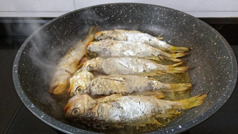 酥炸小黄鱼,锅里多放一点油,放一点点生姜片下小梅鱼煎。