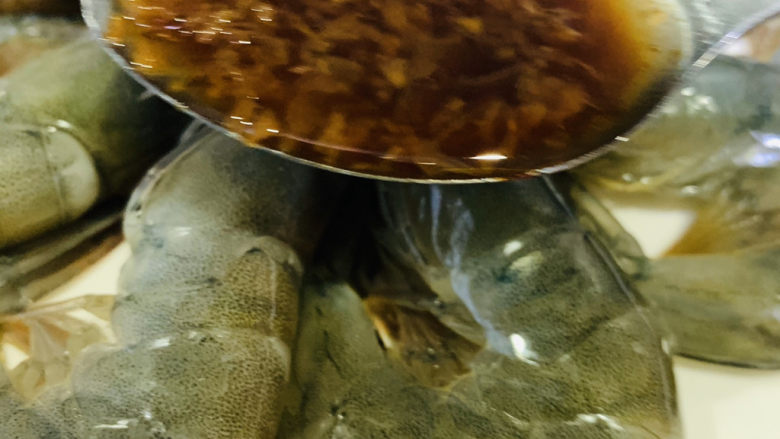 蒜蓉蒸大虾,用勺子,把炒好的蒜蓉浇在每只虾上;