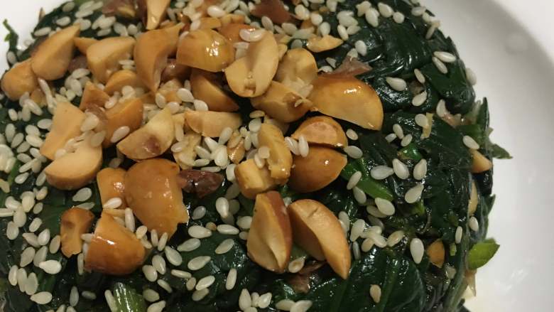 菠菜拌花生米,取一个小碗装满菠菜,然后倒扣在盘子里,上面在撒上花生碎和白芝麻