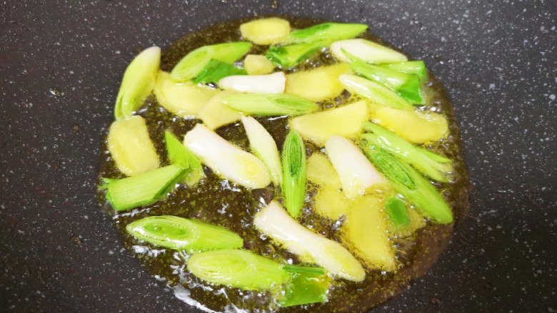 麻辣干锅虾,炒锅内倒适量的食用油烧热,下入蒜苗茎部和生姜片爆香。