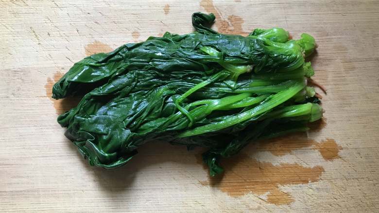 菠菜拌花生米,将菠菜攥干水分放粘板上,用刀切碎段