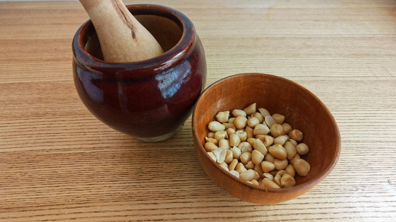 菠菜拌花生米,烤好的花生米晾凉后去掉花生皮。取一半的花生米放入蒜臼中捣碎。