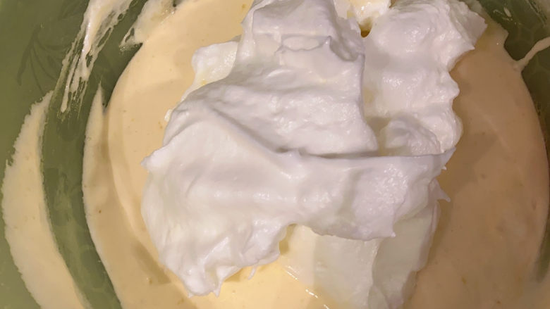 草莓蛋糕,将三分之一蛋白霜加入到蛋黄盆里,用翻拌手法混合均匀,左手转动盆右手从下往上翻,直到蛋白霜消失