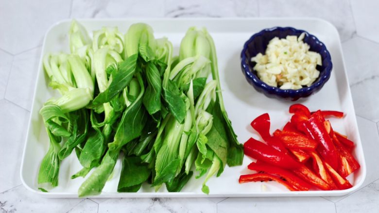 蒜蓉小油菜,把小油菜用刀一切两半,红椒去籽后切条,<a style='color:red;display:inline-block;' href='/shicai/ 2794'>大蒜</a>去皮切碎。