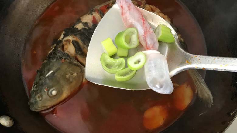 炖草鱼,炖到锅中鱼肉变色,汤汁渐少时,将鱼泡和留下的葱段放入锅中,盖上锅盖,进一步去腥增香