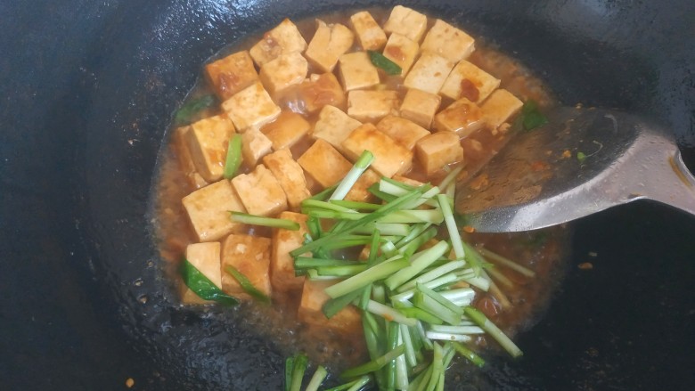 韭菜炒豆腐,水快耗干时，放入韭菜根部翻炒