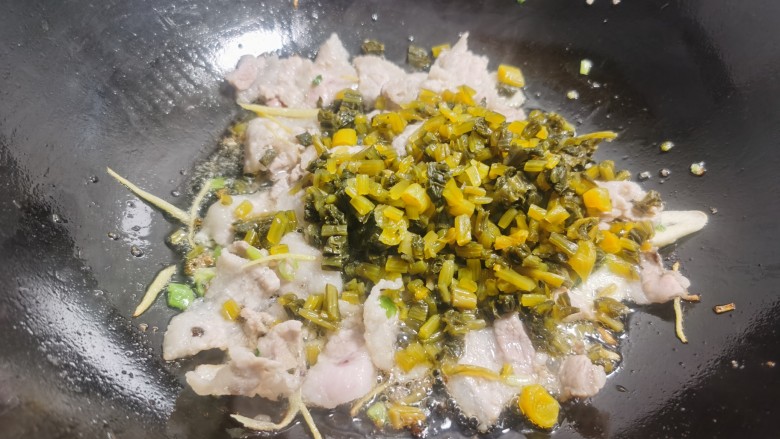雪菜炒春笋,当肉片炒至颜色变白时,加入雪菜翻炒。