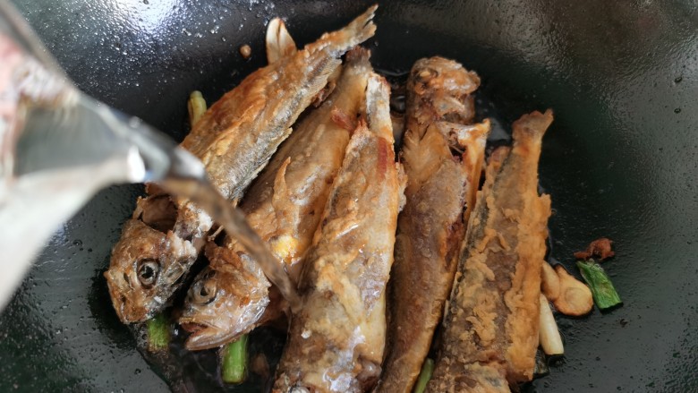红烧小黄鱼,放入煎好的小黄鱼,倒入开水至鱼身的一半。