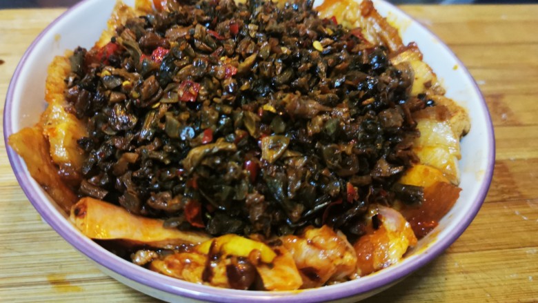 四川烧白,将炒好的咸菜铺在蒸碗中间,留出肉片的边缘