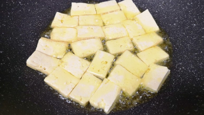 韭菜炒豆腐,炒锅内倒适量的食用油烧热,下入豆腐块中火煎制。