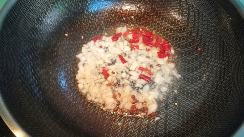 干煸四季豆,放入蒜蓉、花椒和干辣椒,炒出香味
