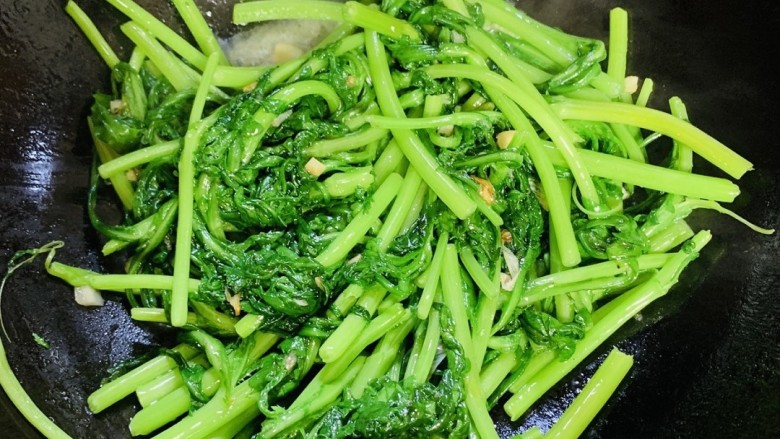 蒜泥茼蒿,先把苘蒿杆放入锅中大火翻炒,顺便把备好的汤汁倒入。
