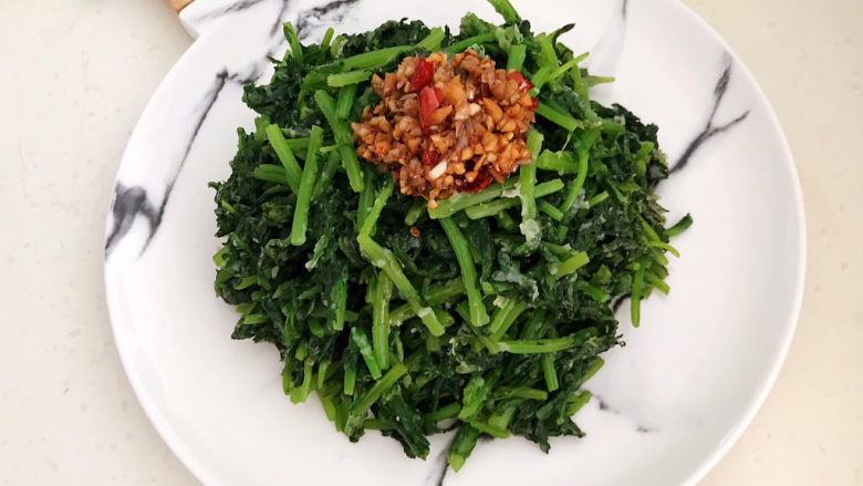 蒜泥茼蒿,把蒸好的茼蒿放入盘里,加入调好的香辣蒜泥即可,吃的时候调匀即可,蒜泥茼蒿就做好了,