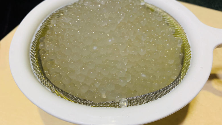 芒果西米捞,打开锅盖西米已全部透明,倒掉煮的水,加凉白开水冲下,用捞勺沥干水,西米已经非常晶莹剔透了;