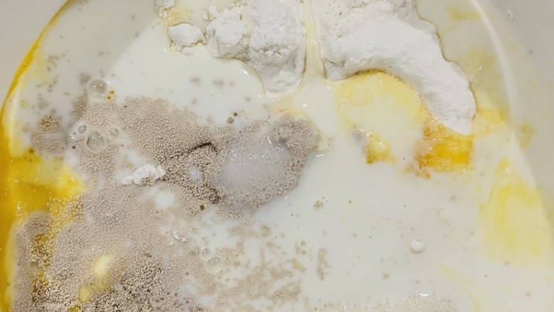 菠萝面包,先做面包部分是,将准备好的高筋粉,鸡蛋,白砂糖,盐,酵母,牛奶依次按顺序倒入容器中