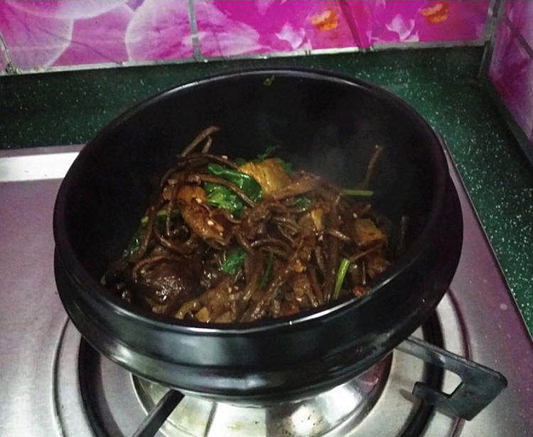 麻辣香锅茶树菇,再撒点芝麻和香菜,最后将它们盛入已烧热的石锅中