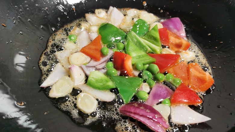 糖醋菠萝排骨,利用锅里底油,加入蒜片和洋葱煸炒出香味,加入青红椒和<a style='color:red;display:inline-block;' href='/shicai/ 148'>豌豆</a>翻炒。