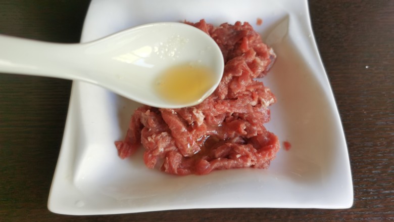 蒜苔炒牛肉,最后再往肉丝里加入两勺的食用油,抓匀后腌制入味。