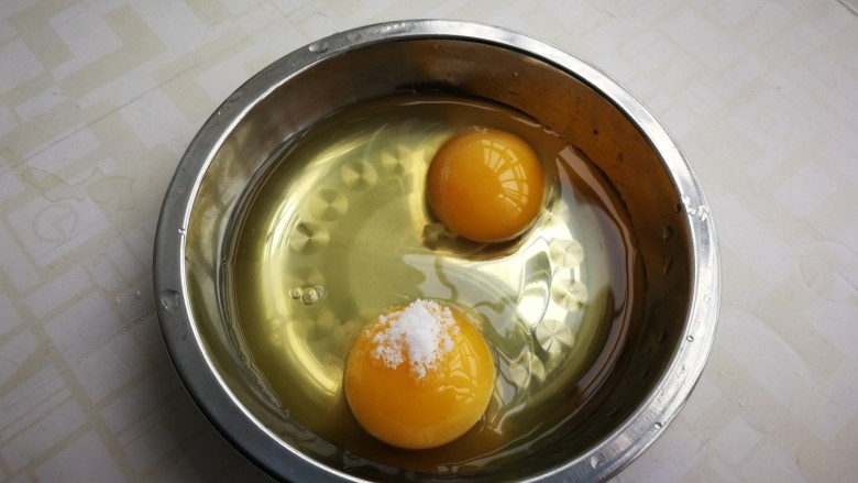茼蒿炒鸡蛋,鸡蛋打入碗中,放少许盐